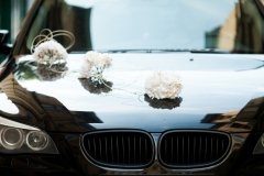 Black BMW decorated with white wedding bouquets